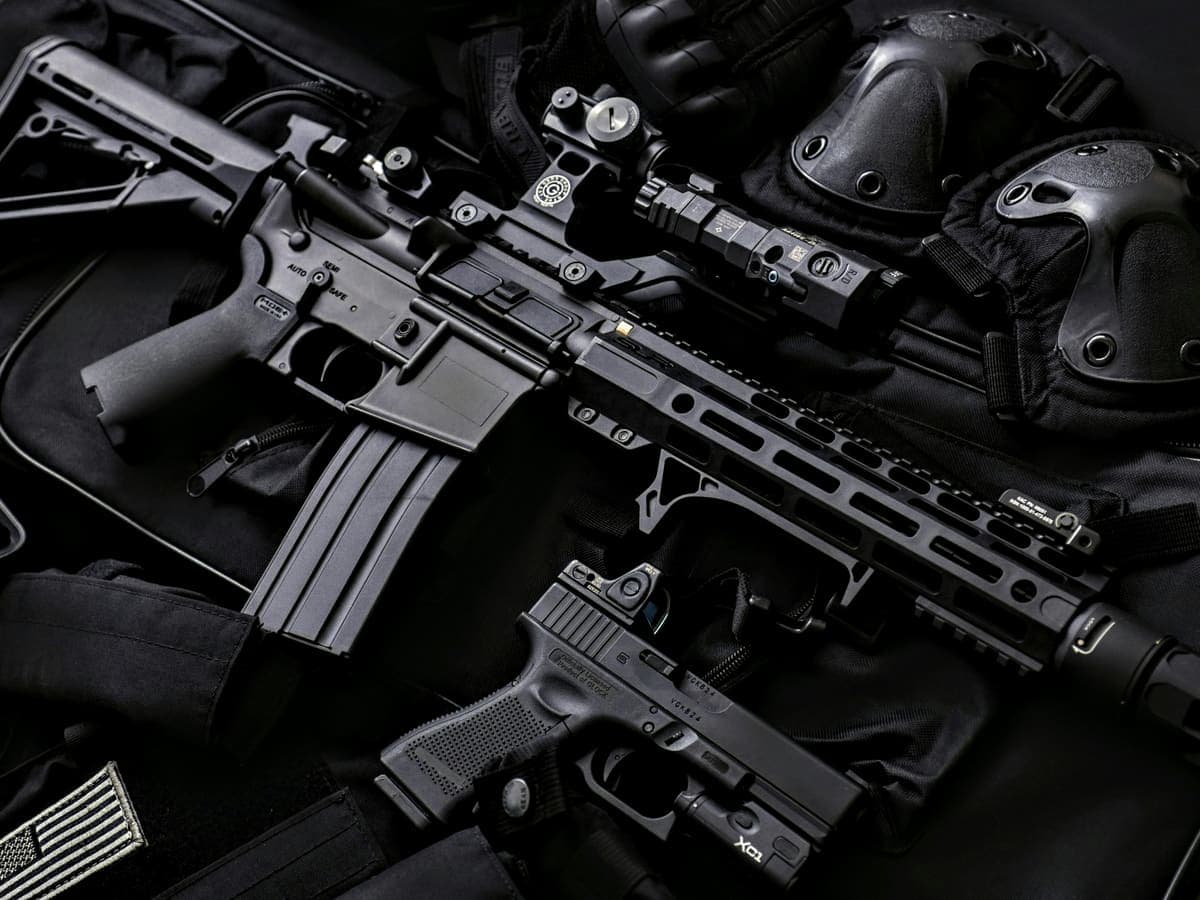 A rifle and pistol laid out with optics mounted on their rails